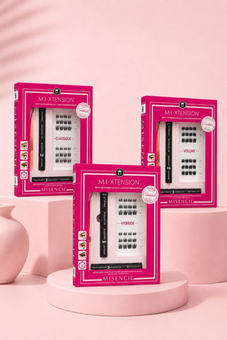 Coffrets MI-XTENSION Misencil Classique, Hybride et Volume sur fond rose pâle, kit d’extensions de cils à poser soi-même pour un effet salon à la maison.