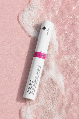 Protecteur cils Misencil Kératine & Panthénol, bouclier quotidien pour extensions de cils, mis en scène sur sable rose Misencil avec mousse d’eau.